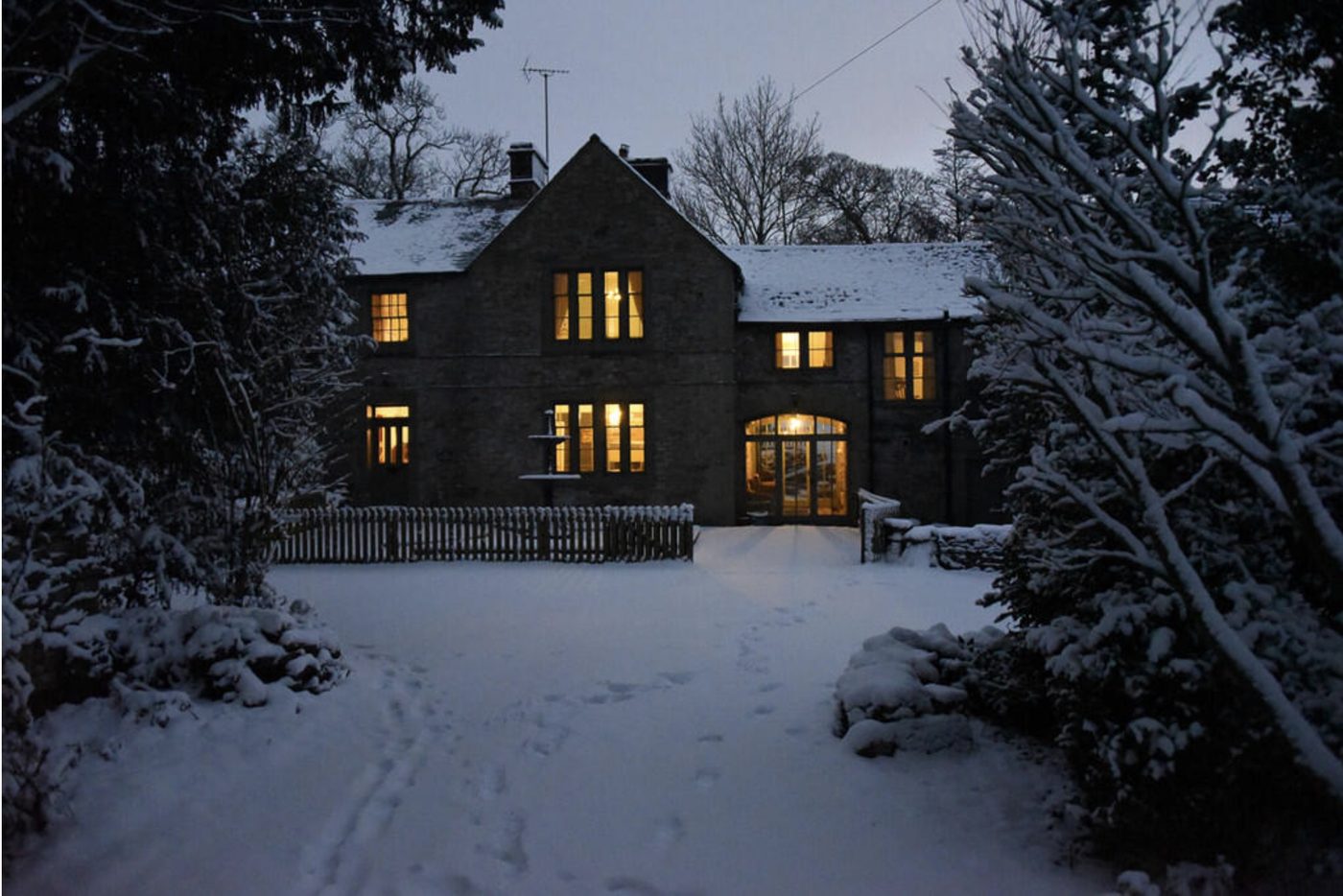 The Rockery in the snow at Christmas, windows glowing